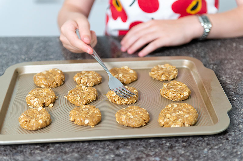 Person preparing ANZAC biscuits on a baking tray