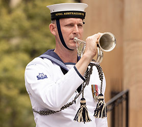 An Australian sailor plays a bugle